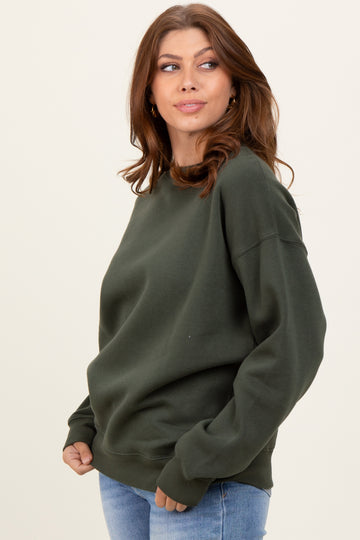 woman wearing an olive green oversized sweatshirt paired with light blue jeans