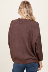woman wearing a brown oversized sweater with a relaxed fit, seen from the back, paired with blue jeans