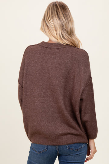 woman wearing a brown oversized sweater with a relaxed fit, seen from the back, paired with blue jeans