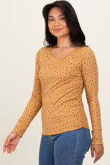 woman wearing a mustard yellow long sleeve top with tiny floral patterns and a scoop neckline, paired with blue jeans