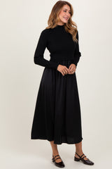 woman wearing a black ribbed crop sweater and a long black skirt, standing in a relaxed pose