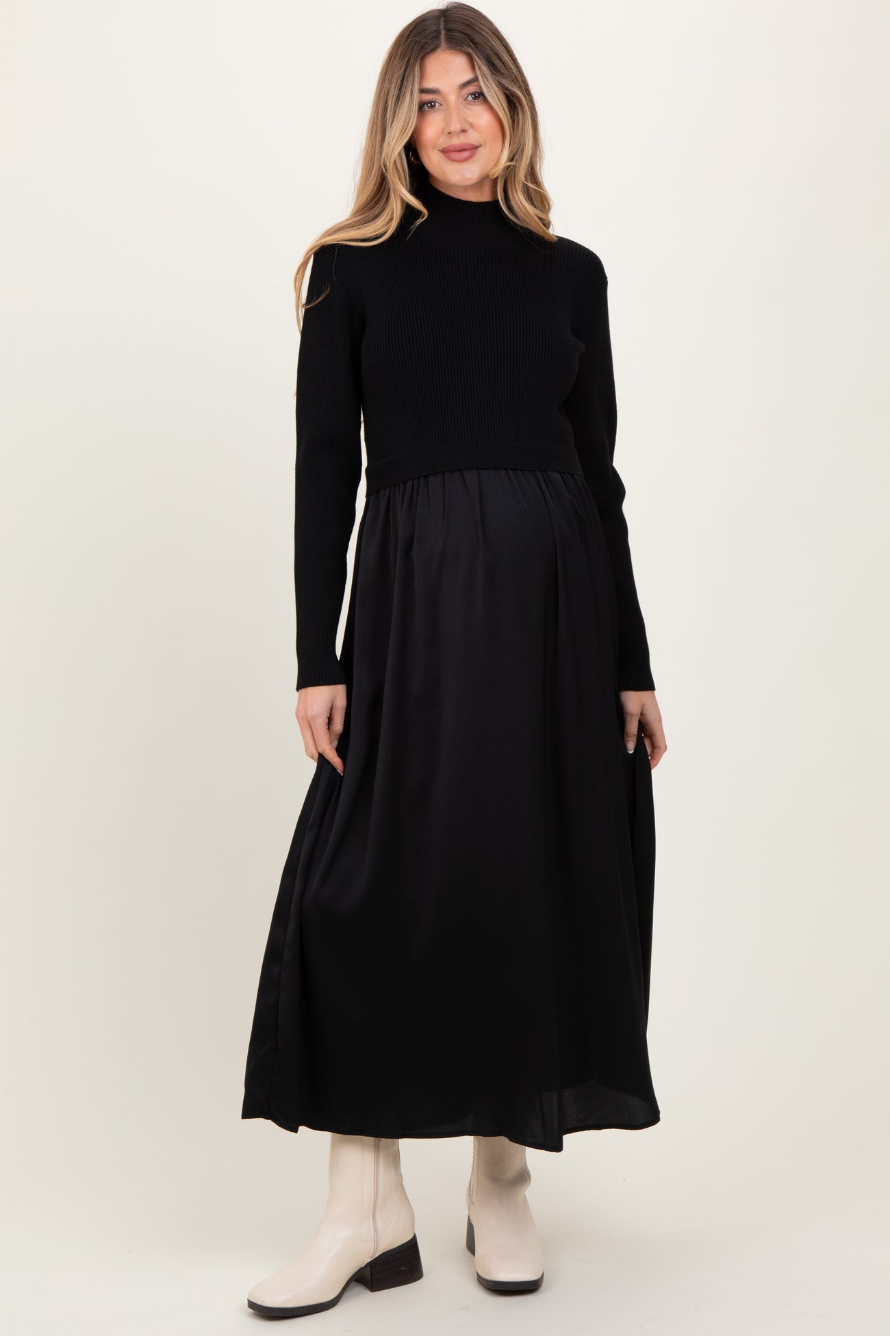 woman wearing a black knit long sleeve maternity dress with a flowing skirt and a visible baby bump