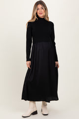 woman wearing a black knit long sleeve maternity dress with a flowing skirt and a visible baby bump