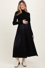 woman wearing a black maternity dress with long sleeves and a fitted bodice, showing her baby bump