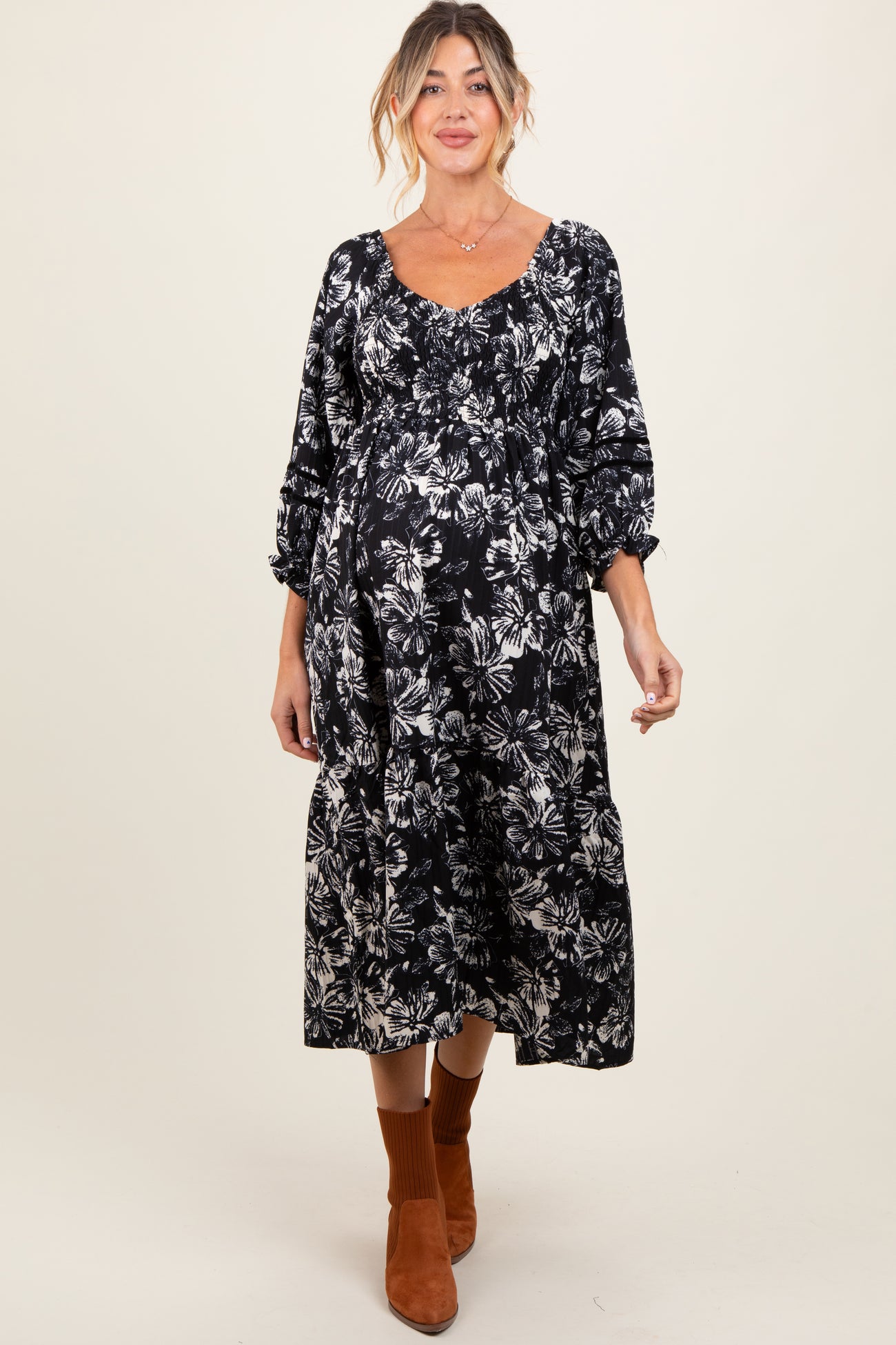 woman wearing a black floral print maternity dress with puff sleeves and a visible baby bump