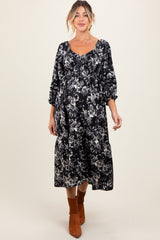 woman wearing a black floral print maternity dress with puff sleeves and a visible baby bump
