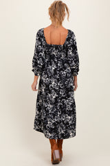 woman wearing a black floral print maternity maxi dress with puffy sleeves and an open back