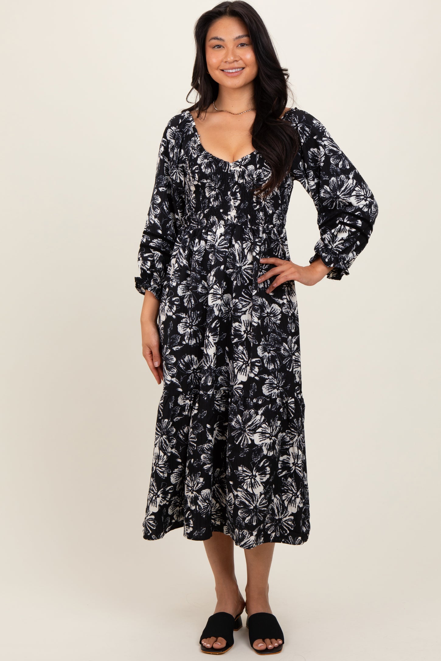 woman wearing a black and white floral midi dress with puffed sleeves and a tiered skirt