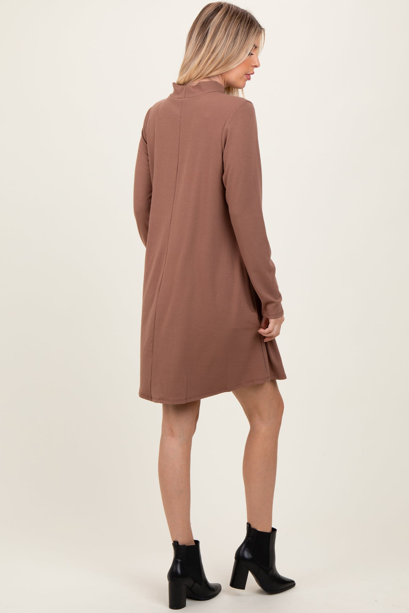 woman wearing a brown long sleeve ribbed dress with a high neckline and side slits, viewed from the back