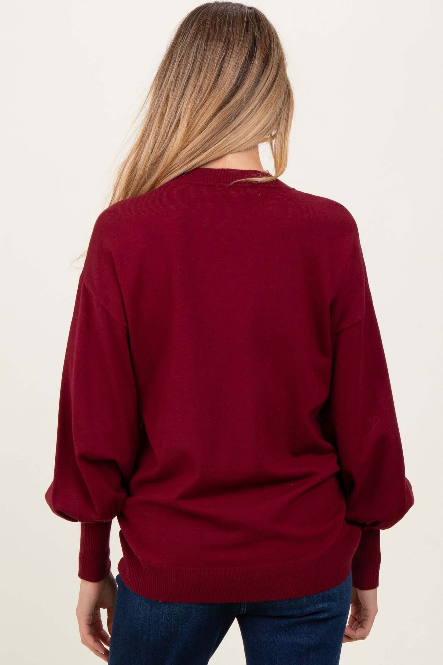 woman wearing a maroon maternity sweater with balloon sleeves, seen from the back