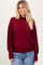 woman wearing a burgundy oversized sweater with balloon sleeves and paired with light blue distressed jeans