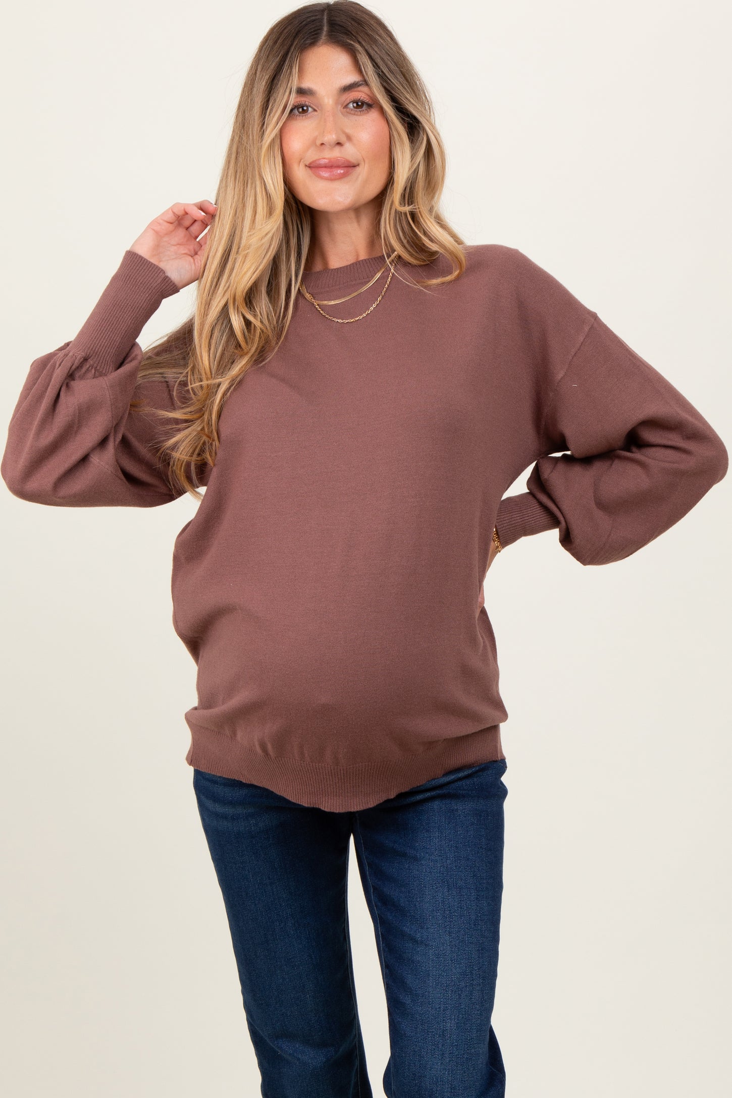 woman wearing a brown maternity sweater with balloon sleeves and a visible baby bump