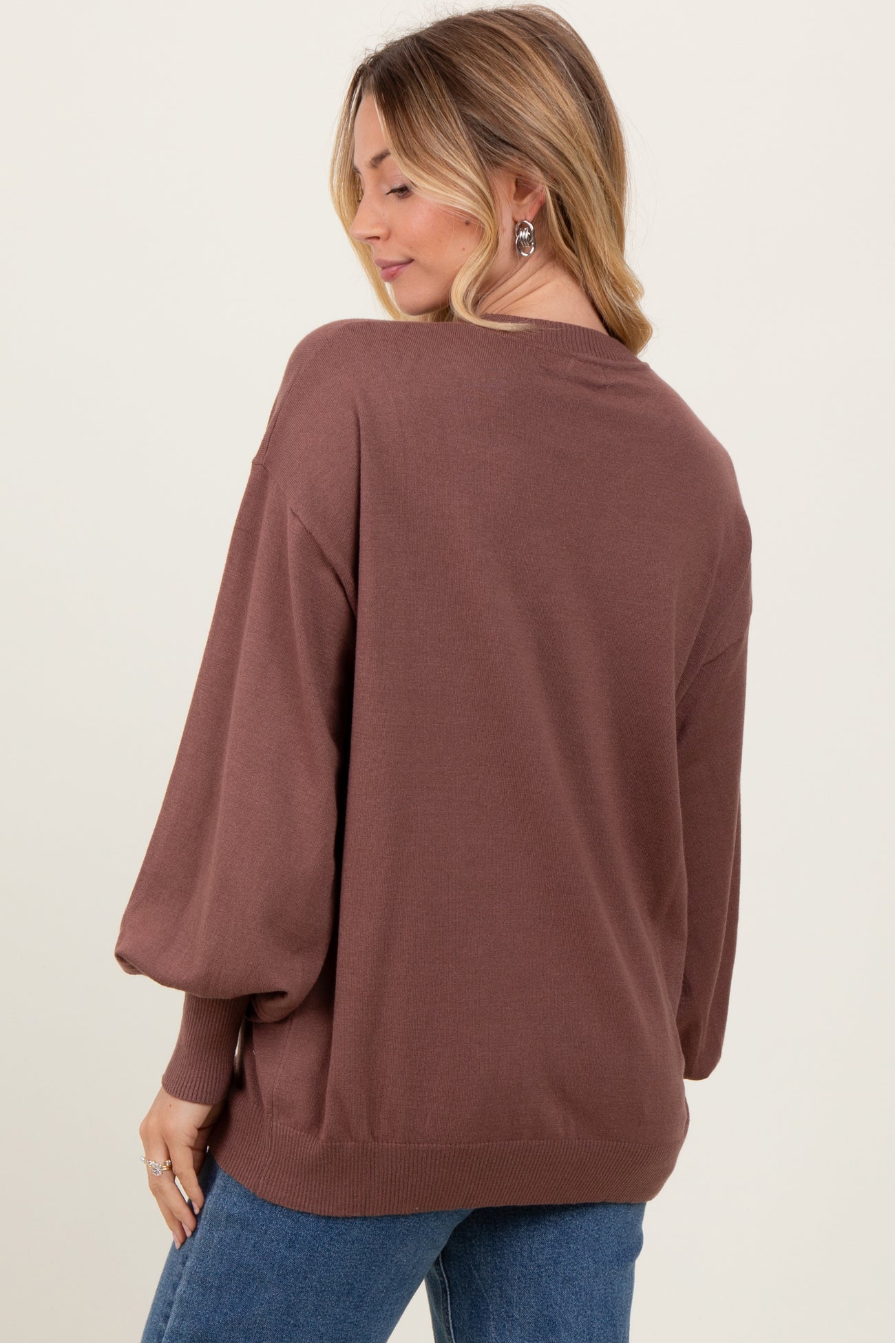 woman wearing a brown oversized sweater with balloon sleeves, viewed from the back