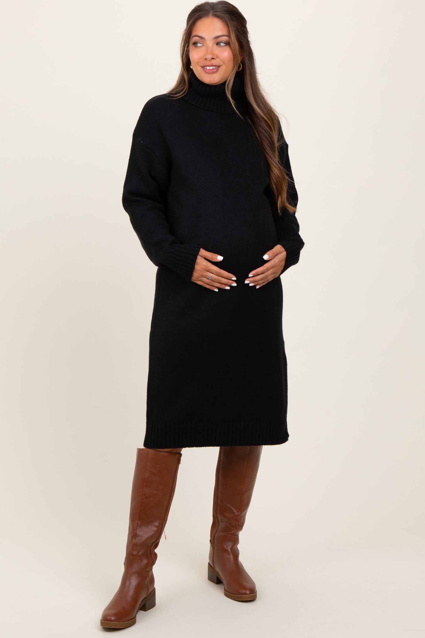 woman wearing a black turtleneck maternity sweater dress and holding her baby bump