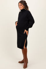 woman wearing a black maternity sweater dress with side slits, showcasing her baby bump and paired with brown knee-high boots