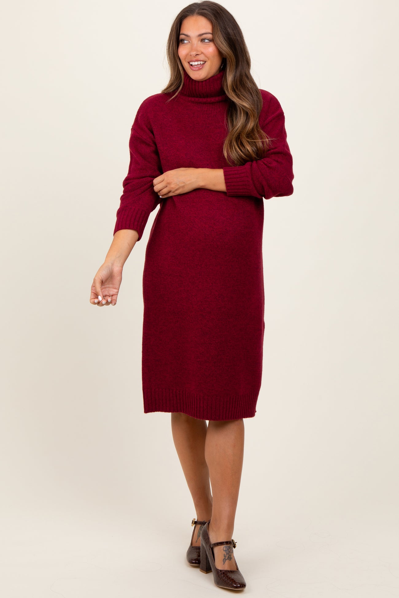 woman wearing a burgundy maternity turtleneck sweater dress with a relaxed fit and a visible baby bump