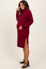 woman wearing a burgundy turtleneck maternity sweater dress with side slits and a visible baby bump