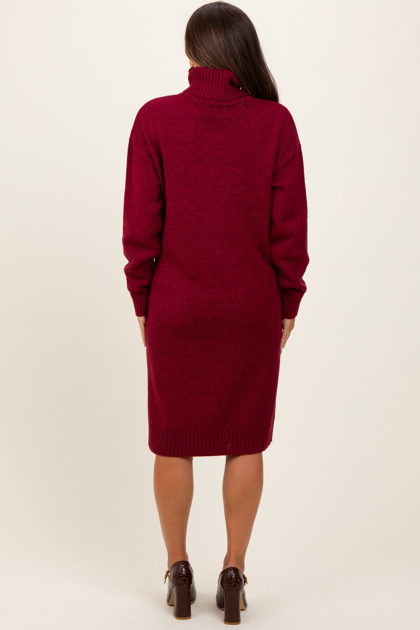 woman wearing a burgundy maternity sweater dress with a turtleneck and long sleeves, seen from the back