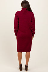 woman wearing a burgundy maternity sweater dress with a turtleneck and long sleeves, seen from the back