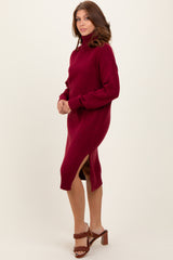 woman wearing a burgundy turtleneck sweater dress with side slits and long sleeves