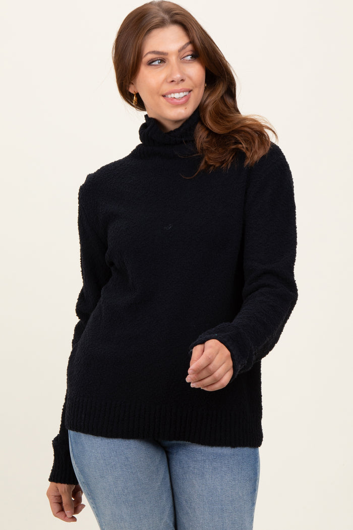 woman wearing a black cozy sweater with a high neckline and ribbed hem, paired with light blue jeans