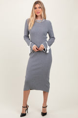 woman wearing a gray ribbed knit midi dress with white ruffled cuffs and black high heels