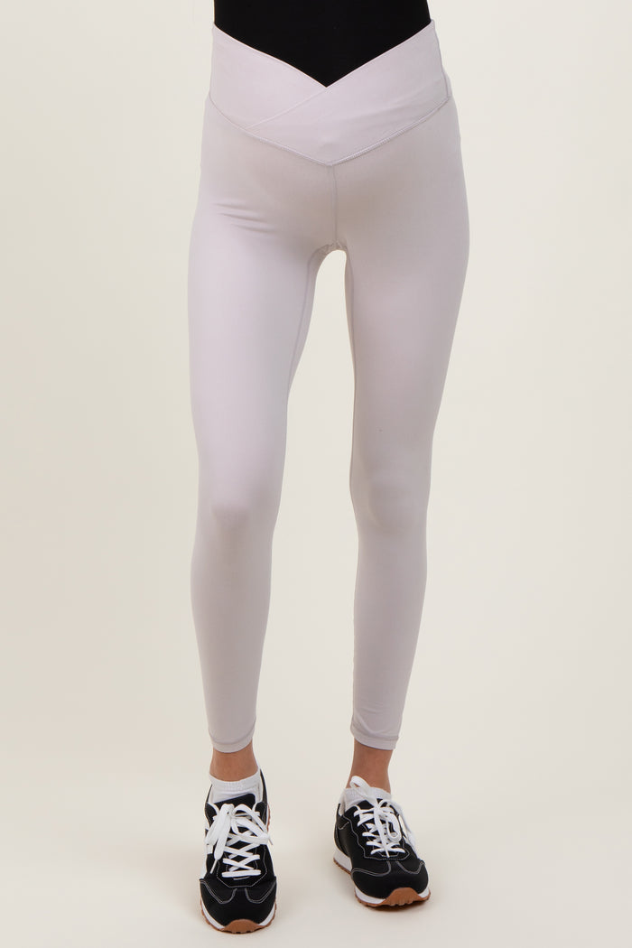 woman wearing light gray maternity leggings with a high waistband and a sleek fit
