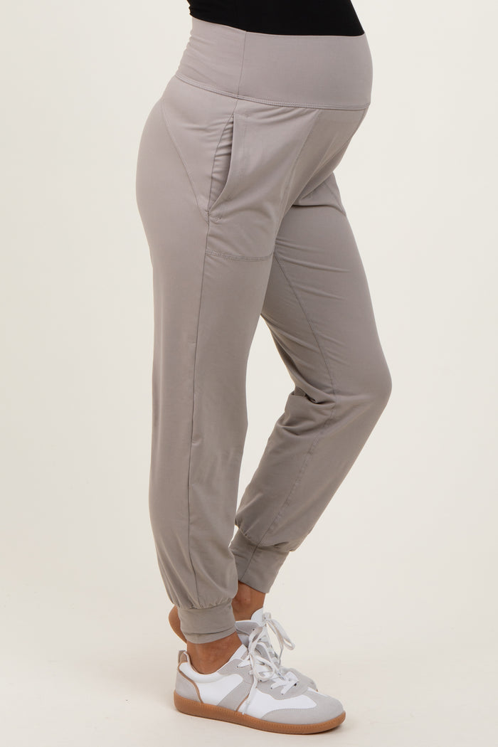 woman wearing light gray maternity joggers with side pockets, showcasing a visible baby bump