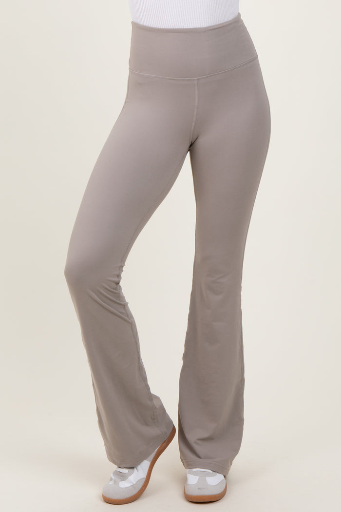 woman wearing light gray flared workout pants with a high waistband and paired with white sneakers