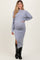 woman wearing a light gray maternity sweater and matching skirt with a side slit, displaying her baby bump