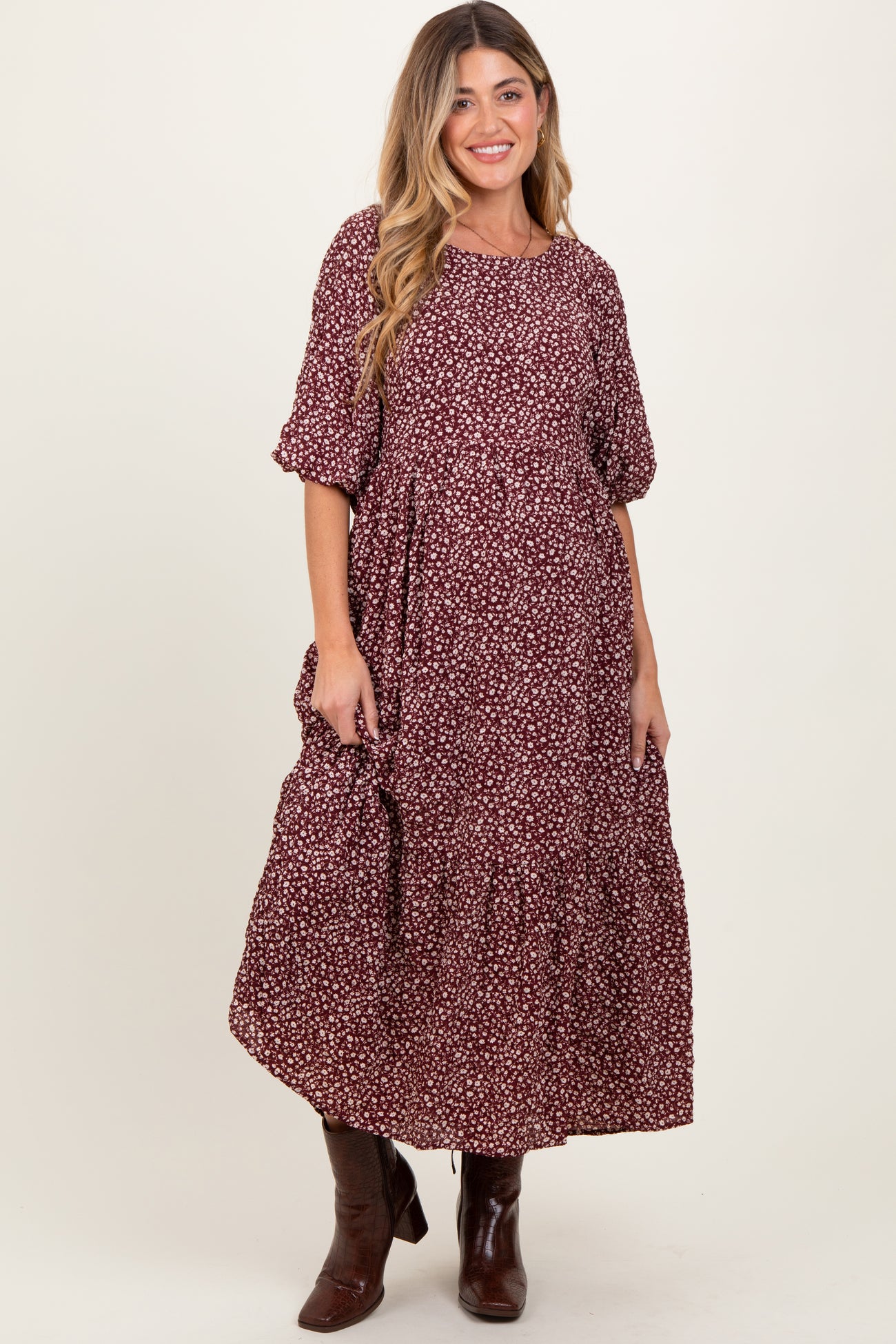 woman wearing a burgundy floral maternity maxi dress with short puff sleeves and tiered ruffles