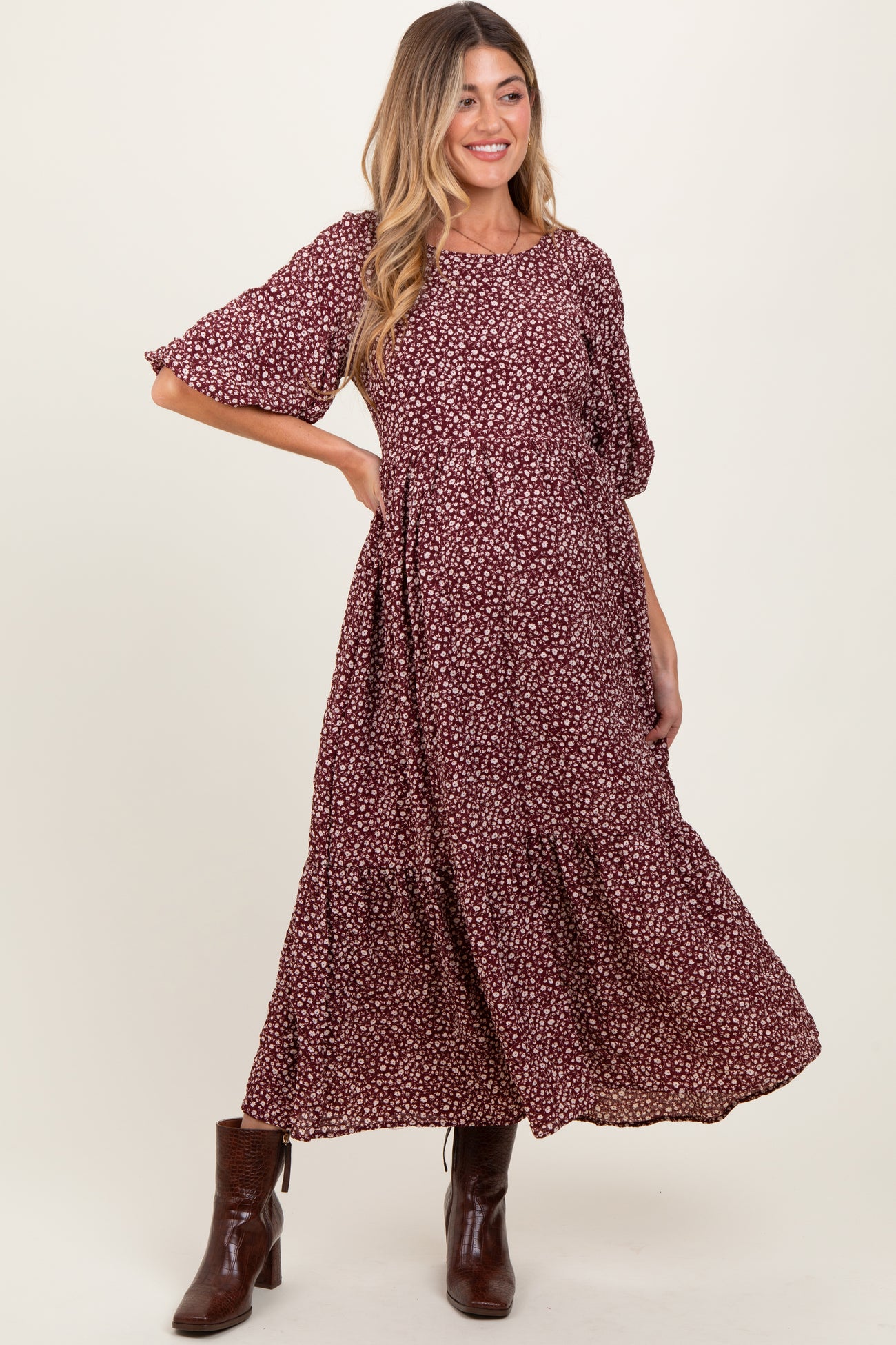 woman wearing a burgundy floral maternity dress with short sleeves and a tiered skirt, showing her baby bump