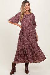 woman wearing a burgundy floral maternity dress with short sleeves and a tiered skirt, showing her baby bump
