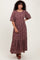 woman wearing a burgundy floral maxi dress with puff sleeves and a tiered skirt