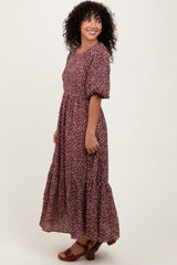 woman wearing a maroon floral maxi dress with puff sleeves and a tiered skirt