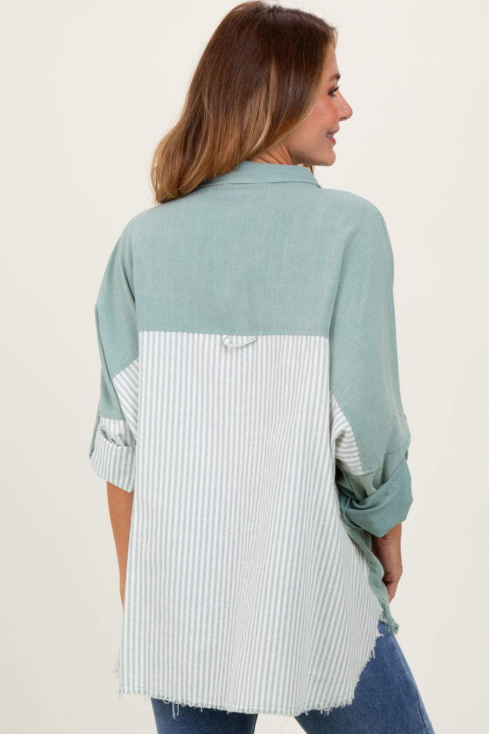 woman wearing a green and white striped oversized button-up shirt, showing a mix of solid and striped patterns on the back