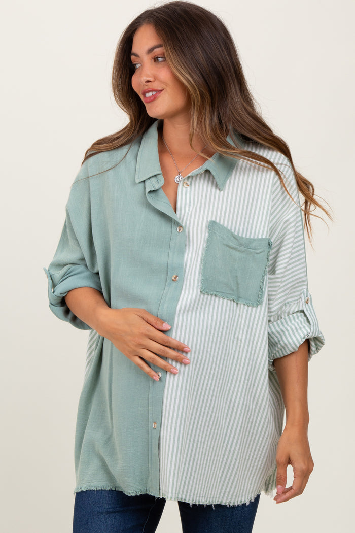 woman wearing a maternity green and white striped oversized button-up shirt and holding her baby bump