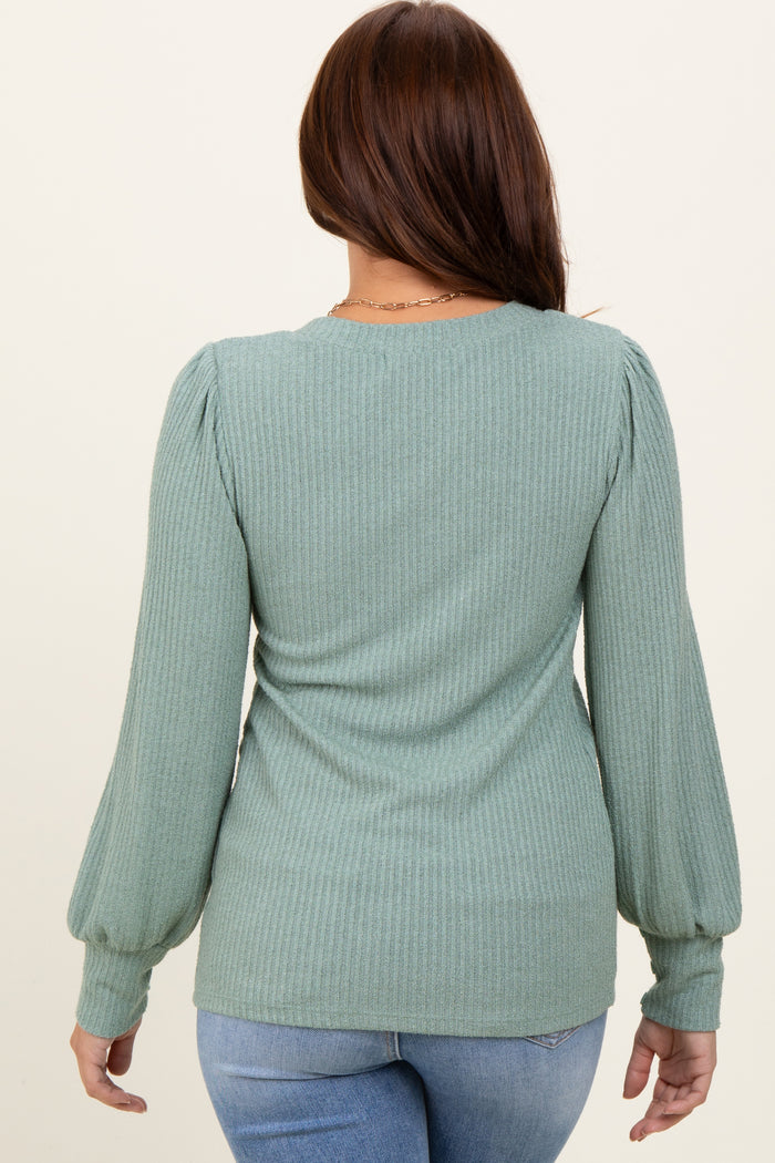 woman wearing a green ribbed long sleeve top with puff sleeves, seen from the back
