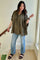 woman wearing a loose-fitting olive green checkered maternity shirt and light blue distressed jeans with black sandals