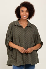 woman wearing an oversized olive green checkered shirt with a button-up front and rolled sleeves