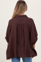 woman wearing a chocolate brown checkered maternity top with a relaxed fit and slightly puffed sleeves