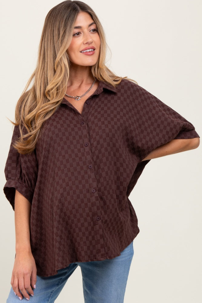 woman wearing a dark brown checkered maternity top with a loose fit and short sleeves, styled with light blue jeans