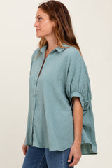 woman wearing a loose-fitting light blue button-up shirt with puffed sleeves and a relaxed silhouette