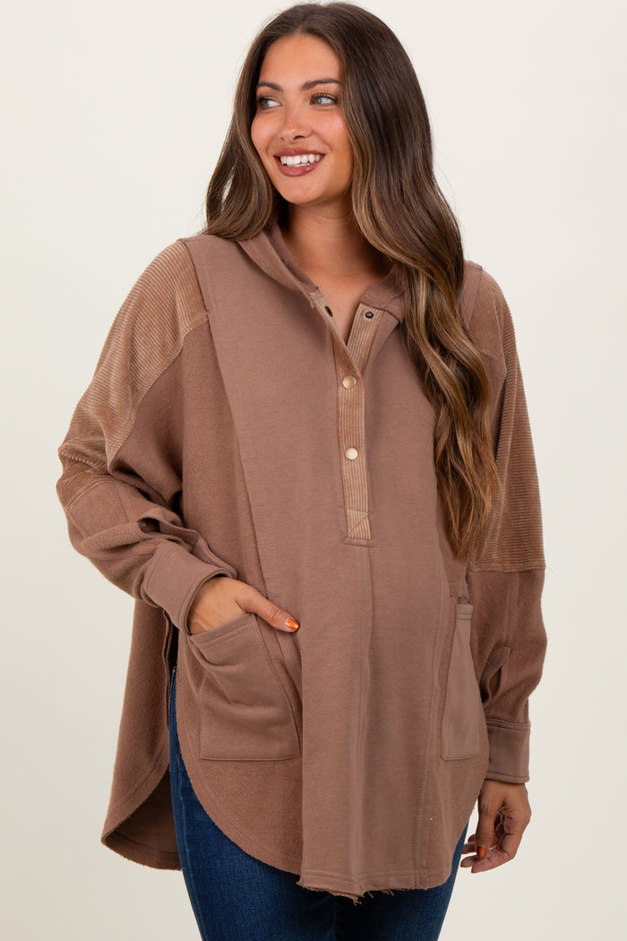 woman wearing a brown maternity hoodie with a button placket and front pockets, featuring a relaxed fit and longer back