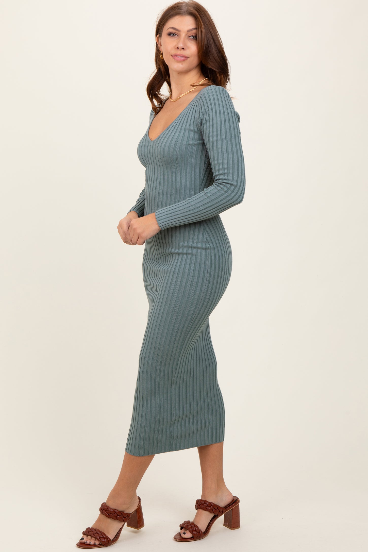 woman wearing a teal ribbed long sleeve midi dress and brown heeled sandals, posing sideways