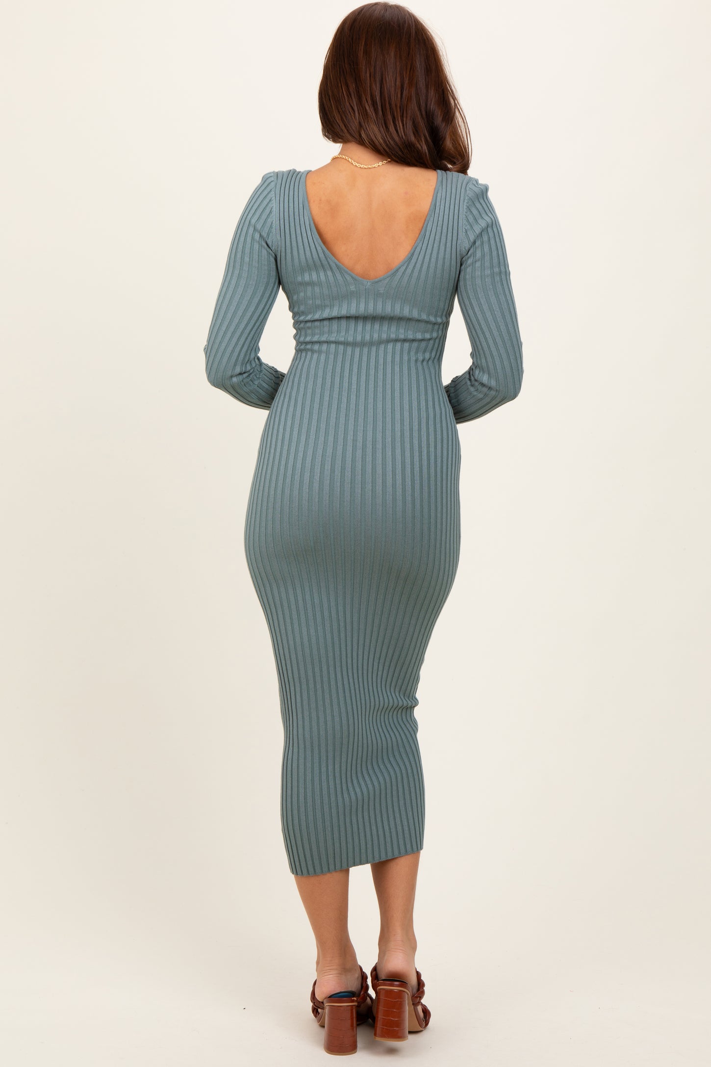 woman wearing a teal ribbed long sleeve midi dress with a low back and fitted silhouette