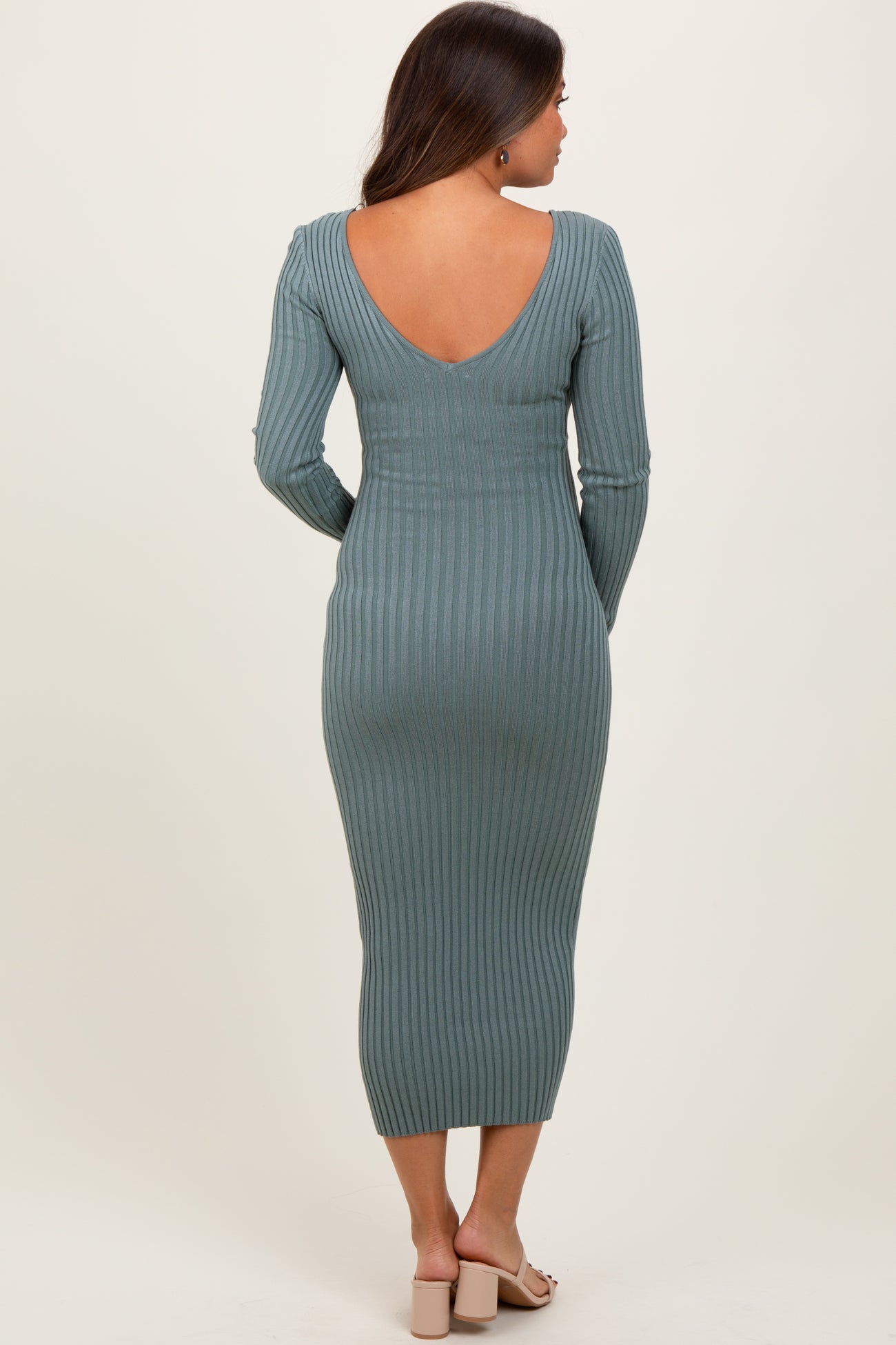 woman wearing a green ribbed maternity dress with a deep v-back and long sleeves