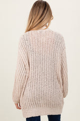 woman wearing a light beige loose knit maternity sweater viewed from the back