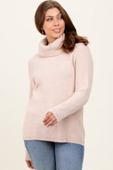 woman wearing a light pink ribbed turtleneck sweater and blue jeans
