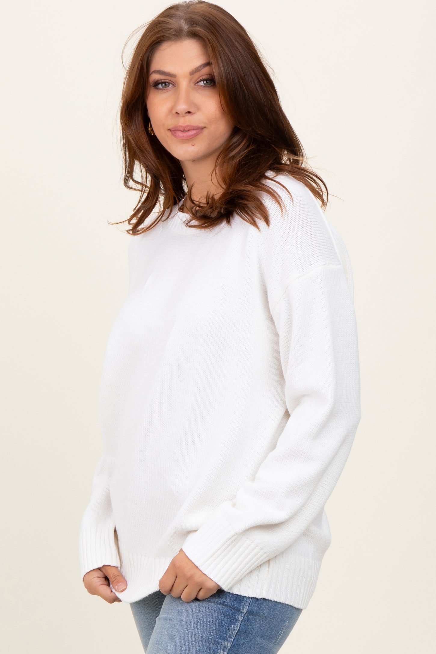 woman wearing a cozy white long sleeve sweater with a relaxed fit and paired with blue jeans